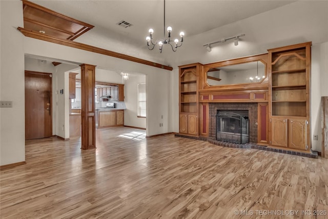 unfurnished living room featuring a notable chandelier, light hardwood / wood-style flooring, and ornate columns