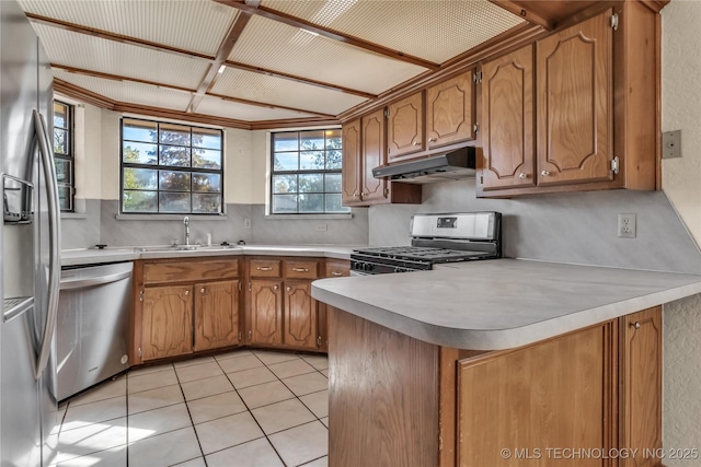 kitchen featuring appliances with stainless steel finishes, kitchen peninsula, light tile patterned flooring, sink, and backsplash