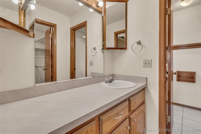 bathroom with a textured ceiling, tile patterned floors, and vanity