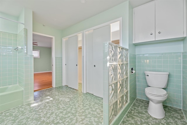 bathroom featuring toilet, walk in shower, and tile walls