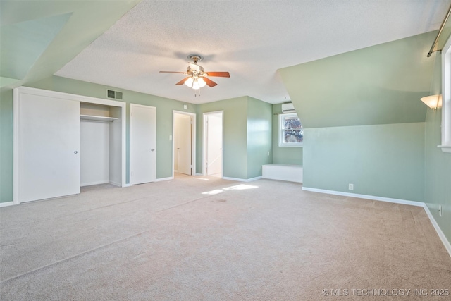 unfurnished bedroom with ceiling fan, light carpet, and a textured ceiling