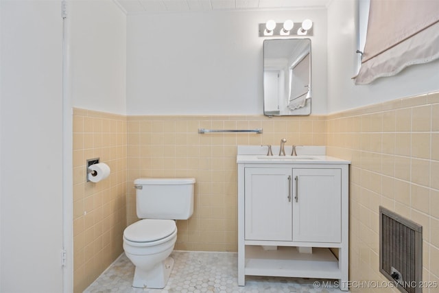 bathroom with toilet, tile patterned floors, vanity, and tile walls