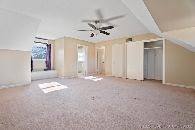 unfurnished bedroom with lofted ceiling, ceiling fan, a wall mounted air conditioner, and light carpet