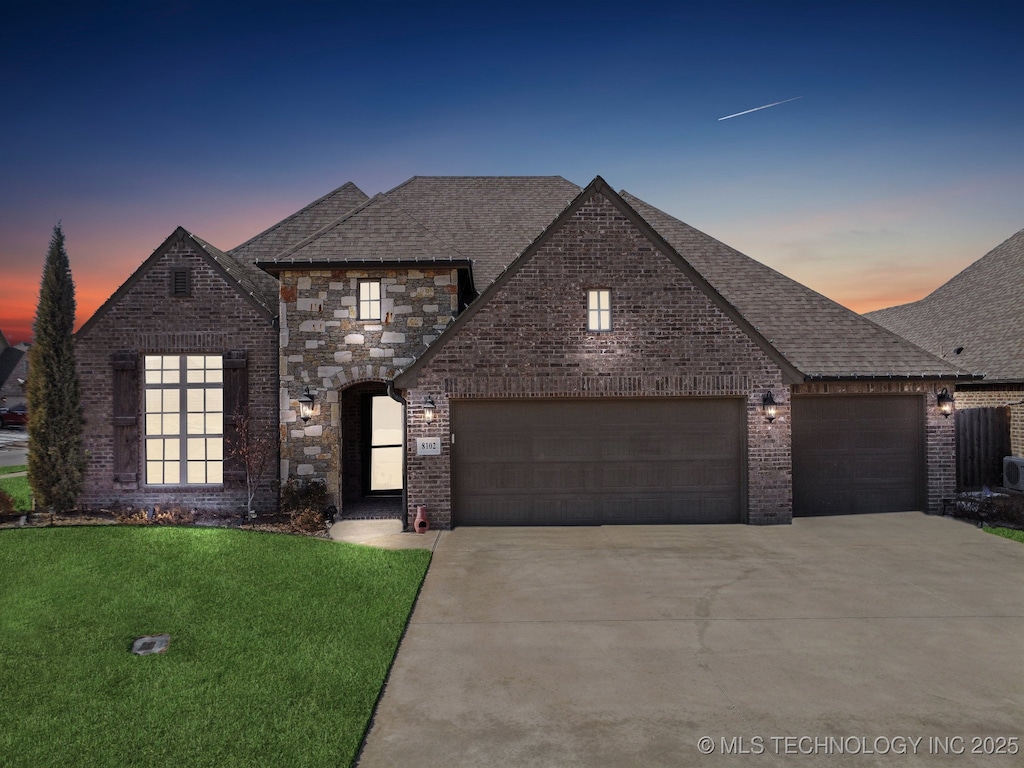 french provincial home featuring a yard and a garage