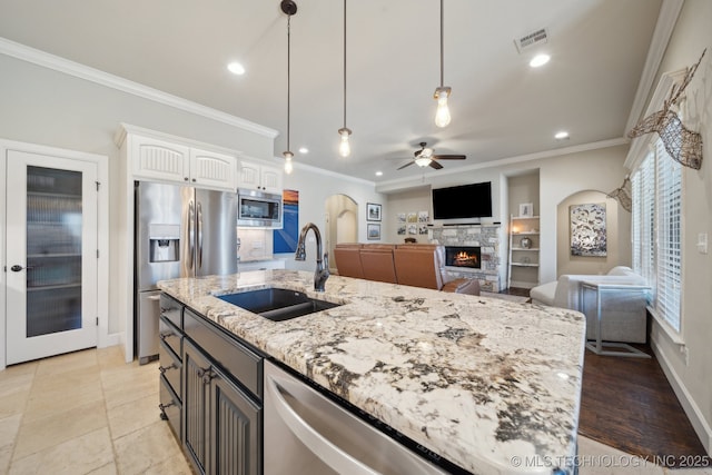 kitchen featuring decorative light fixtures, white cabinetry, a fireplace, appliances with stainless steel finishes, and sink