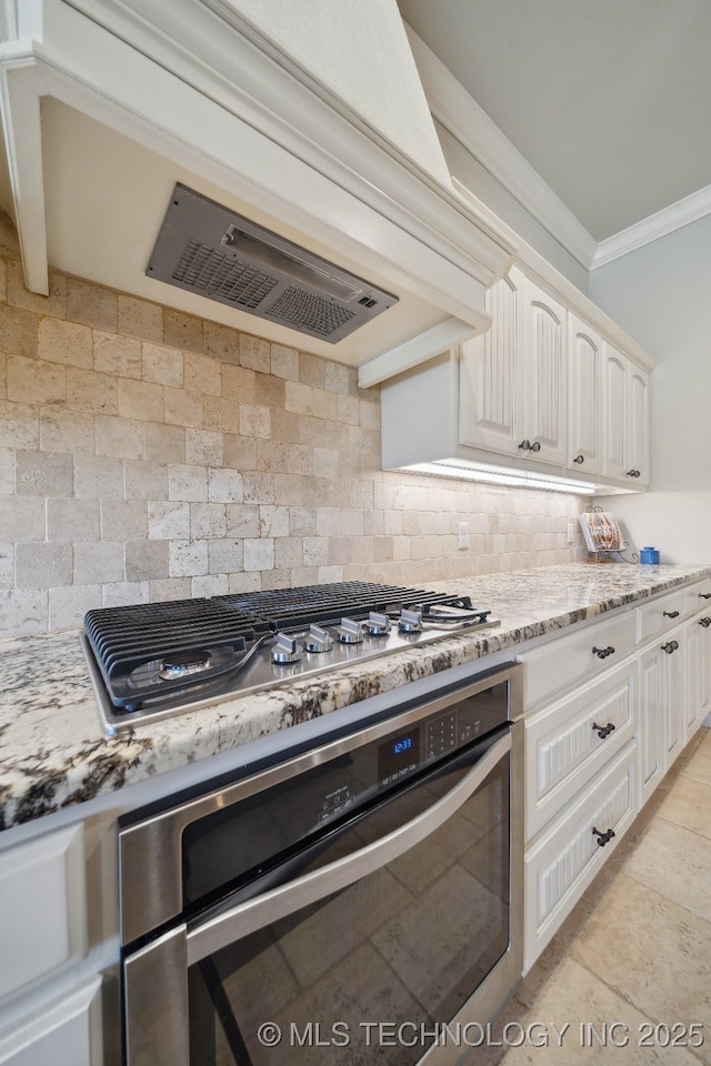 kitchen featuring light stone counters, stainless steel appliances, decorative backsplash, crown molding, and white cabinetry