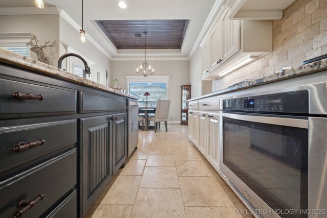 kitchen with stainless steel oven, pendant lighting, decorative backsplash, white cabinetry, and an inviting chandelier