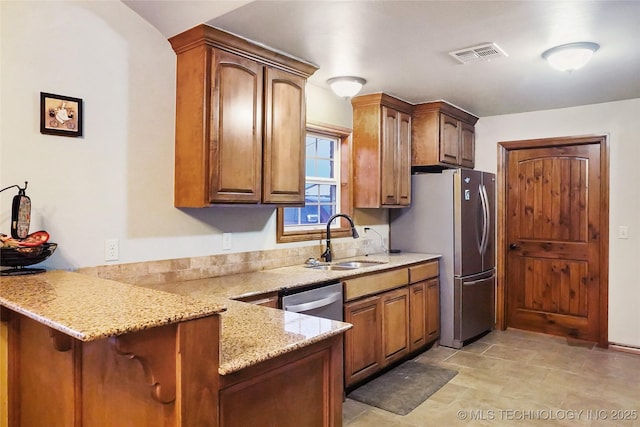 kitchen featuring kitchen peninsula, light stone countertops, sink, and stainless steel appliances