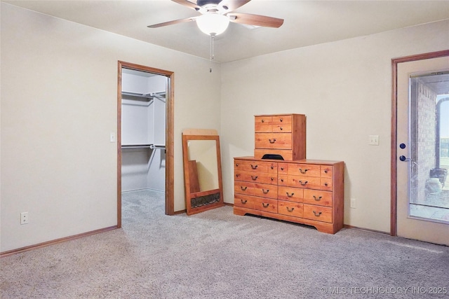 carpeted bedroom with ceiling fan, a closet, and a walk in closet