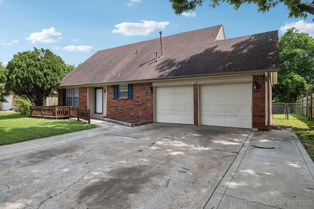 view of front facade with a front yard, a garage, and a wooden deck