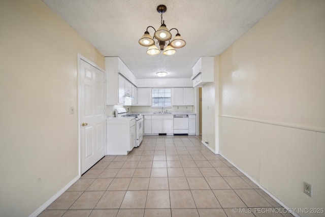 kitchen with white appliances, a textured ceiling, a chandelier, light tile patterned floors, and white cabinets