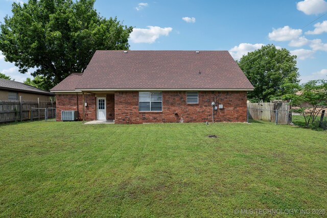 rear view of property featuring central air condition unit and a lawn