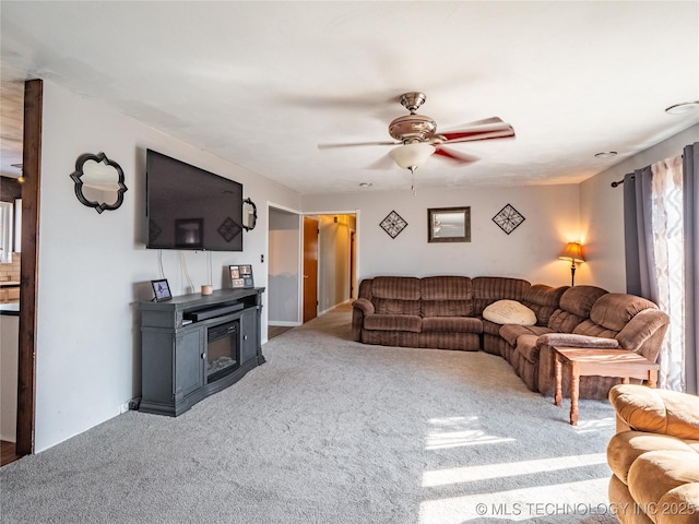 living room with carpet floors, ceiling fan, and a wood stove