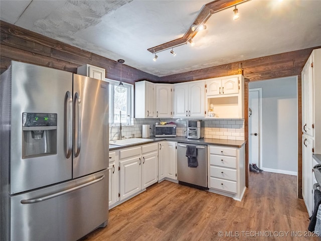 kitchen featuring sink, white cabinetry, light wood-type flooring, tasteful backsplash, and appliances with stainless steel finishes