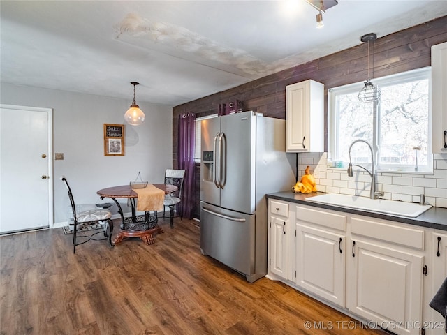 kitchen featuring hanging light fixtures, stainless steel refrigerator with ice dispenser, backsplash, white cabinetry, and sink