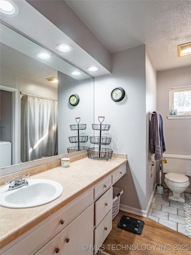 bathroom featuring toilet, vanity, and a textured ceiling