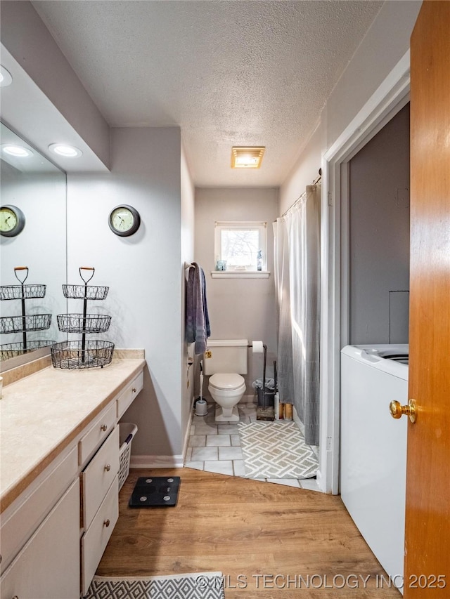 bathroom featuring hardwood / wood-style floors, vanity, washer / dryer, a textured ceiling, and curtained shower