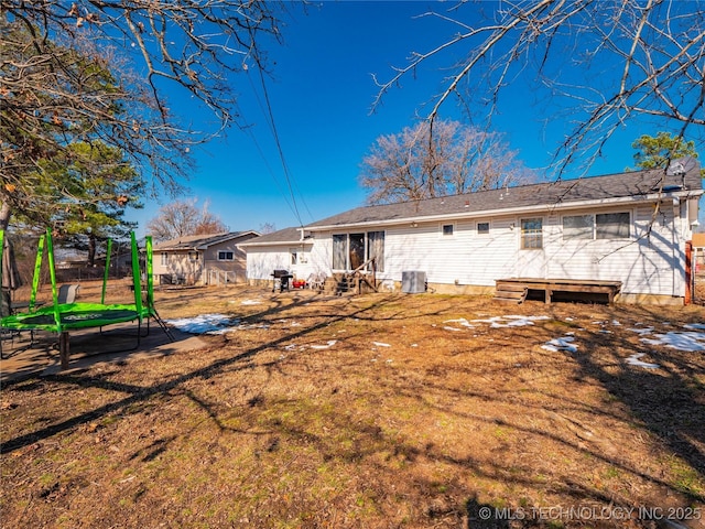 back of property featuring a yard, central AC unit, and a trampoline