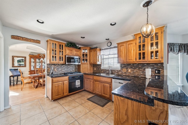 kitchen with kitchen peninsula, appliances with stainless steel finishes, light tile patterned floors, and sink