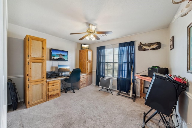 carpeted home office featuring ceiling fan