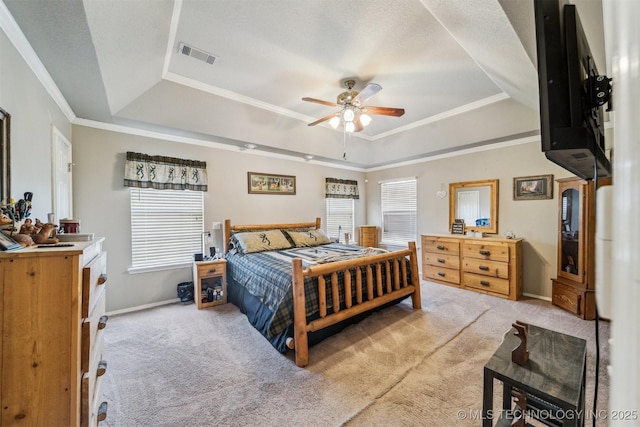 bedroom with ceiling fan, ornamental molding, light carpet, and a tray ceiling