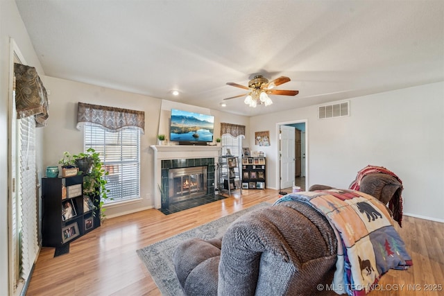 living room featuring a fireplace, ceiling fan, and light wood-type flooring