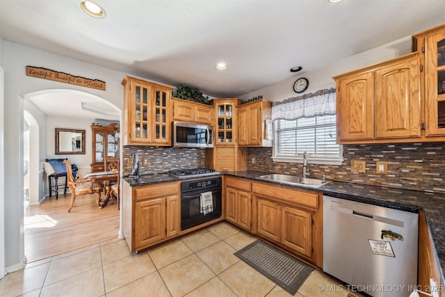 kitchen featuring appliances with stainless steel finishes, dark stone countertops, sink, and light tile patterned floors