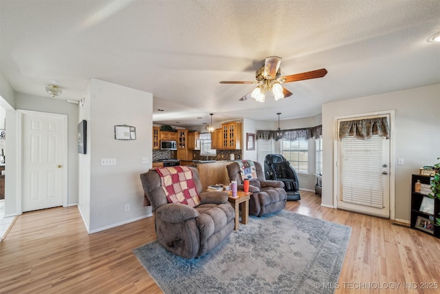 living room featuring a textured ceiling, light hardwood / wood-style flooring, and ceiling fan with notable chandelier