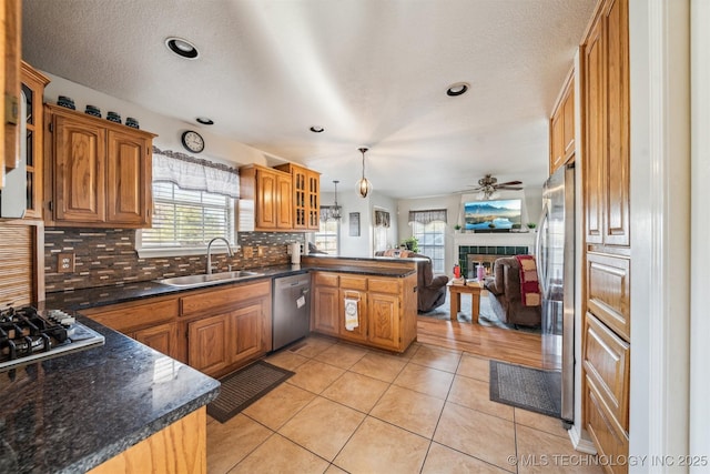 kitchen with sink, light tile patterned floors, kitchen peninsula, backsplash, and appliances with stainless steel finishes