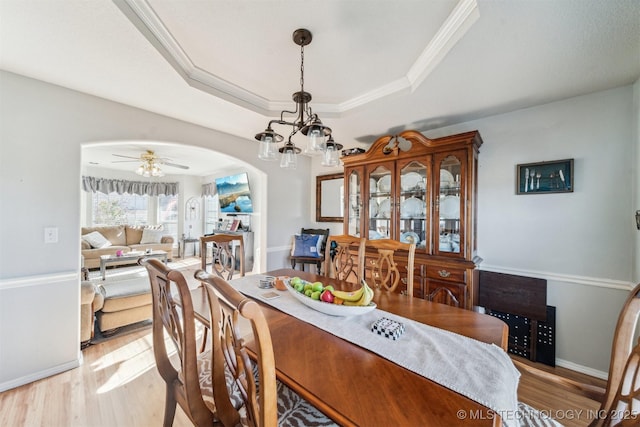 dining room featuring ceiling fan with notable chandelier, a raised ceiling, crown molding, and light hardwood / wood-style flooring