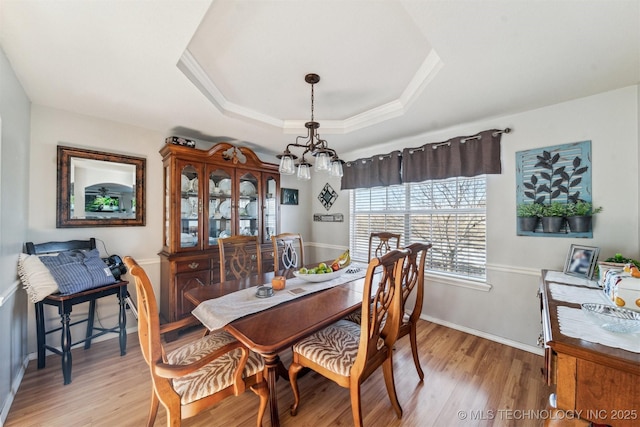 dining room featuring a chandelier, light wood-type flooring, and a tray ceiling