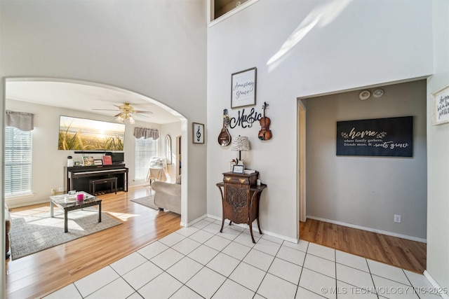 entryway with a towering ceiling, ceiling fan, and light tile patterned floors