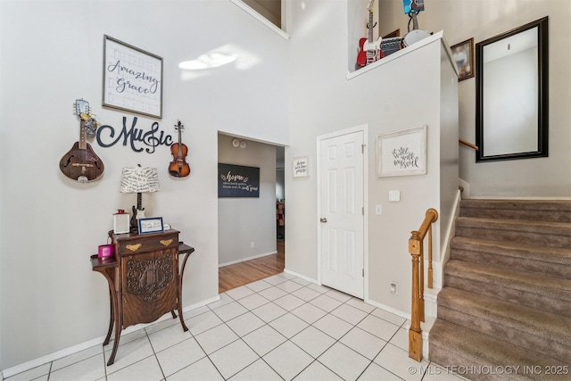 foyer entrance featuring a towering ceiling and light tile patterned floors