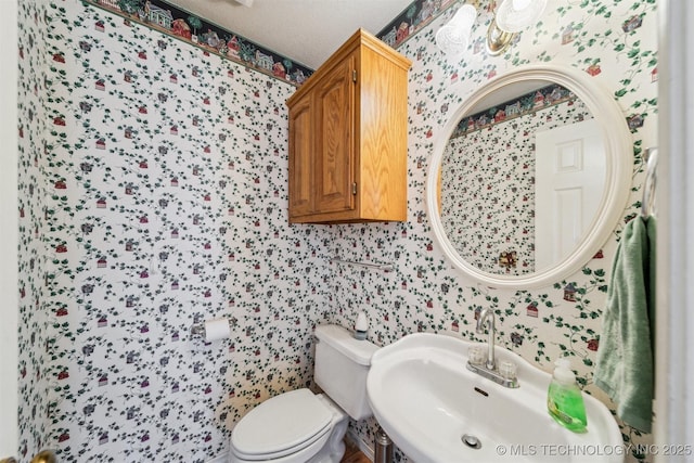 bathroom featuring toilet, a textured ceiling, and sink