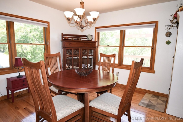 dining space featuring wood-type flooring, a wealth of natural light, and a notable chandelier