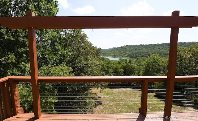 wooden deck featuring a wooded view and a water view