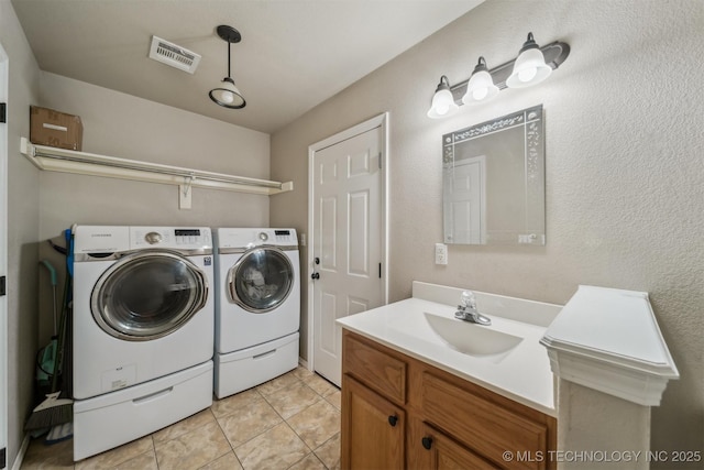 washroom featuring washing machine and clothes dryer, light tile patterned floors, and sink