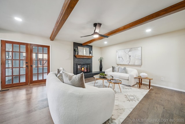 living room with hardwood / wood-style flooring, french doors, beam ceiling, a fireplace, and ceiling fan