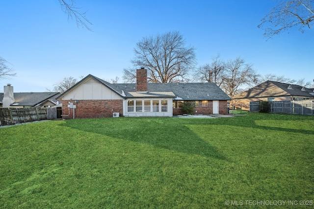 back of house featuring a sunroom and a lawn