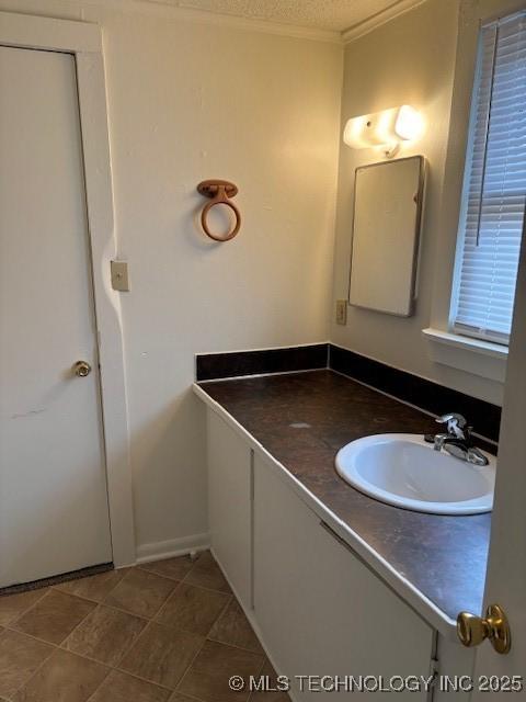 bathroom featuring tile patterned flooring, crown molding, a textured ceiling, and vanity