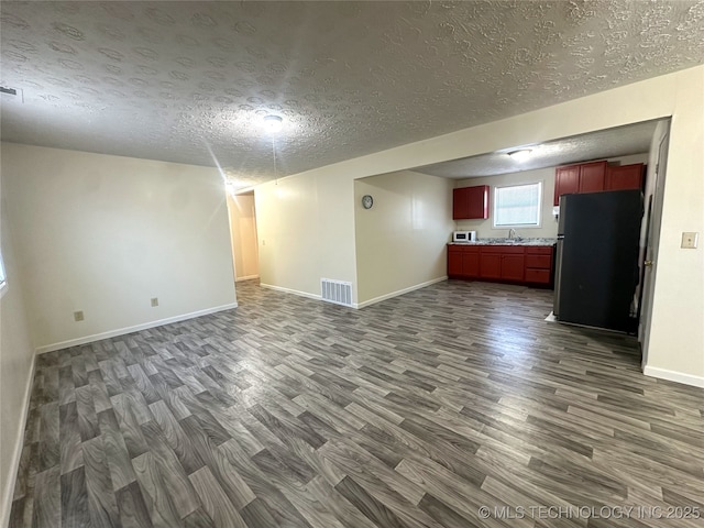 unfurnished living room featuring a textured ceiling, sink, and dark hardwood / wood-style floors