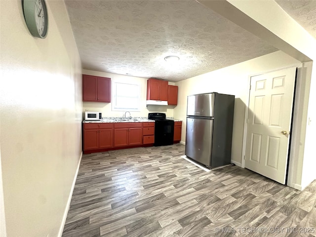 kitchen featuring a textured ceiling, black / electric stove, stainless steel fridge, light wood-type flooring, and sink