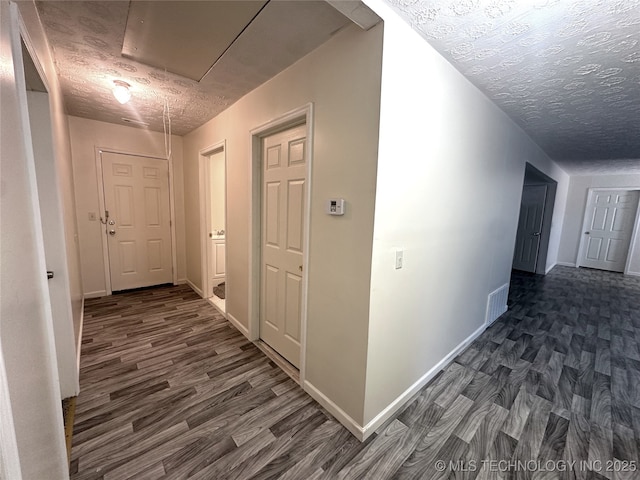 hallway featuring a textured ceiling and dark hardwood / wood-style floors