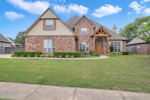 craftsman house featuring a chimney, fence, brick siding, board and batten siding, and a front yard