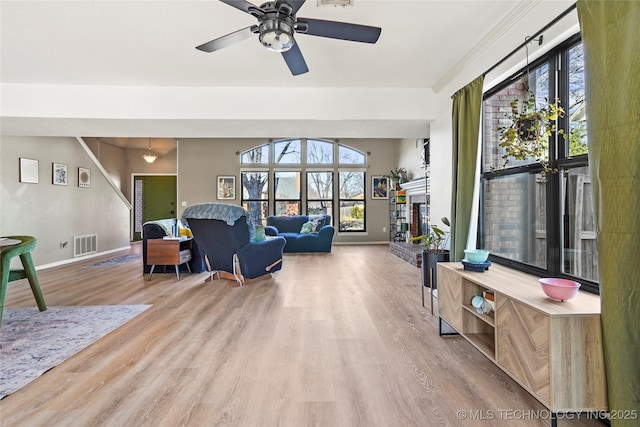 living room with ceiling fan, light hardwood / wood-style floors, and a brick fireplace