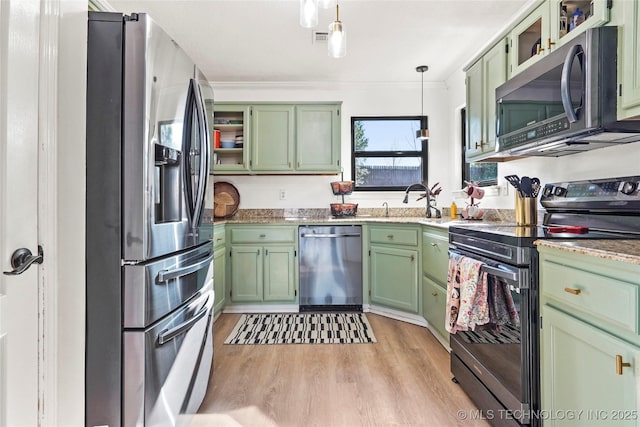 kitchen featuring stainless steel appliances, green cabinetry, decorative light fixtures, and light wood-type flooring