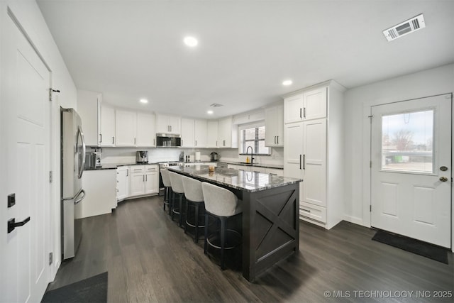 kitchen with stainless steel appliances, sink, white cabinetry, a breakfast bar area, and a kitchen island