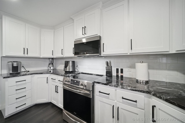 kitchen featuring backsplash, dark hardwood / wood-style flooring, white cabinetry, appliances with stainless steel finishes, and dark stone countertops