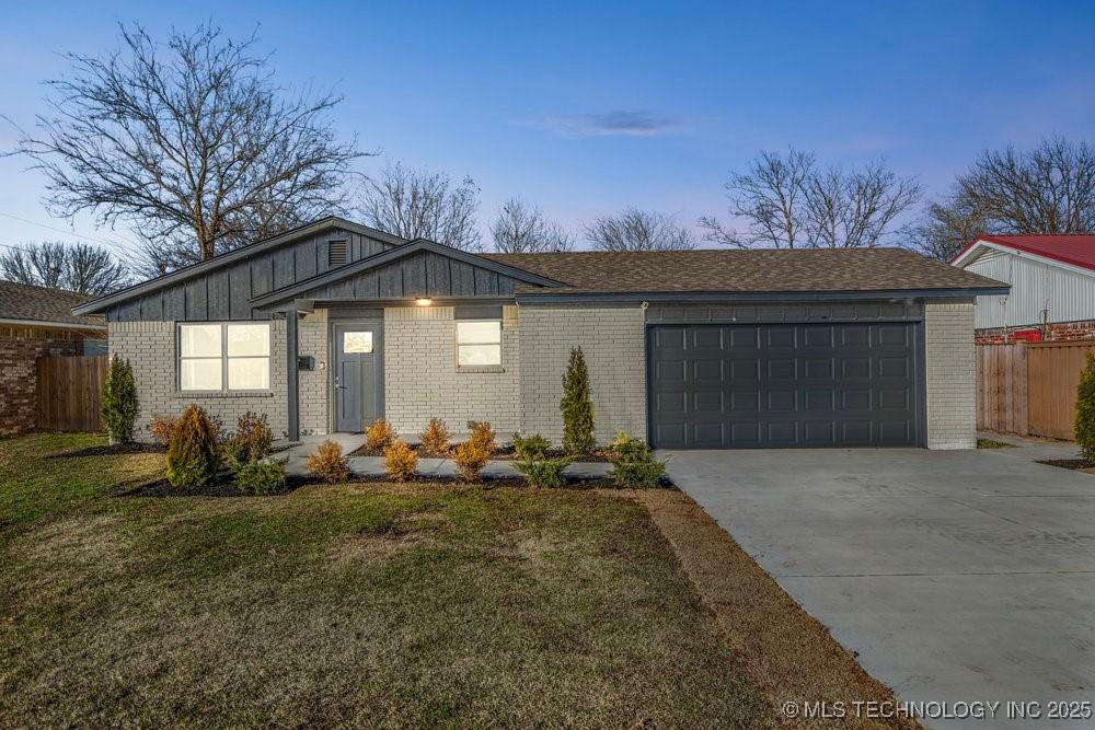 ranch-style home featuring a garage and a yard