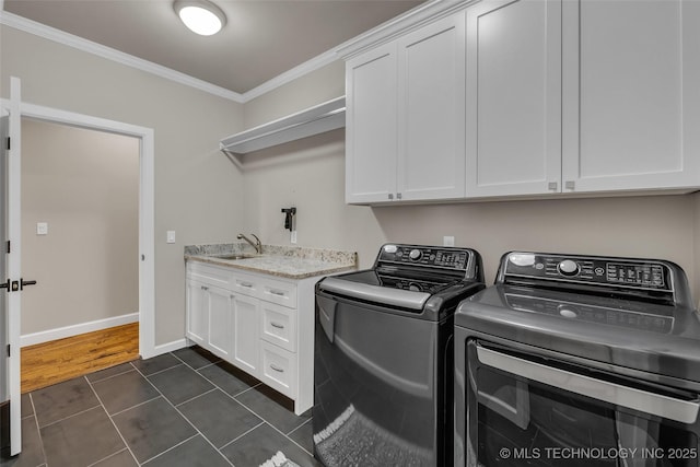 clothes washing area featuring washer and dryer, cabinets, dark tile patterned flooring, and crown molding